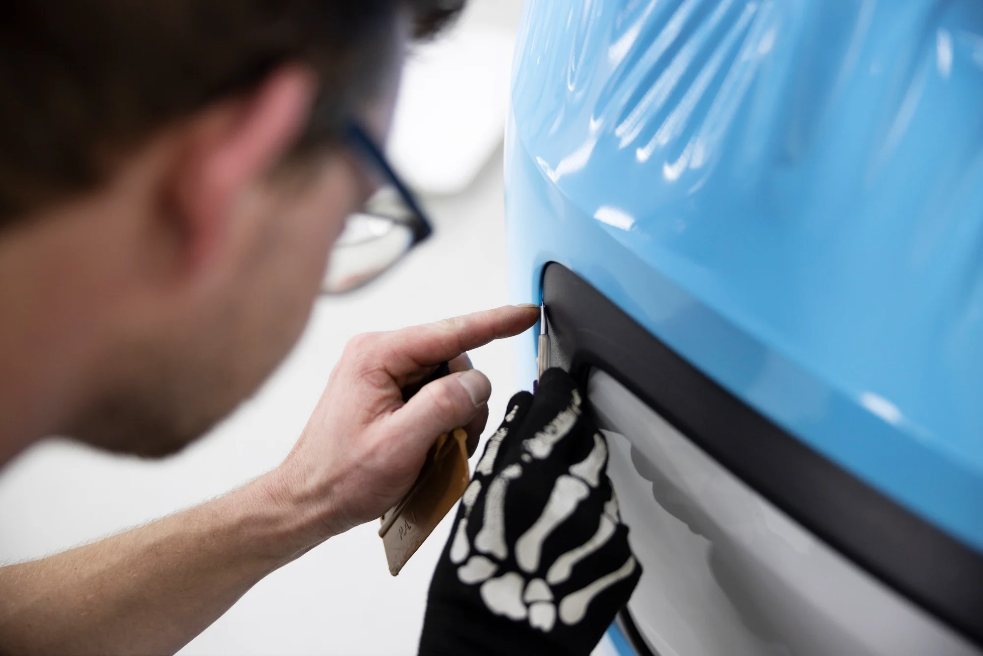 Installer tucking light blue wrap film into a panel edge